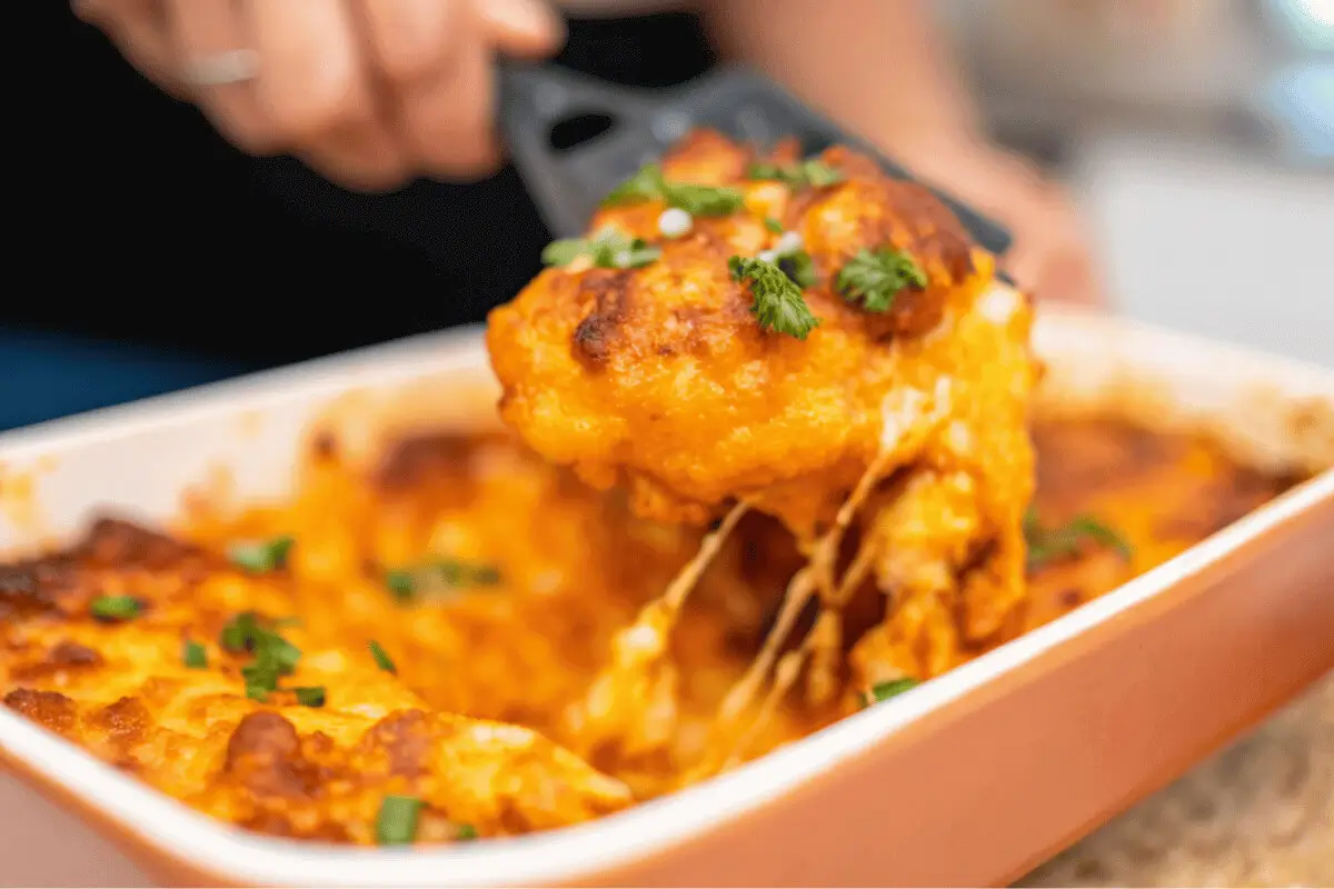 Low carb dump and bake pasta casserole being served from a baking dish with melted cheese and green onions